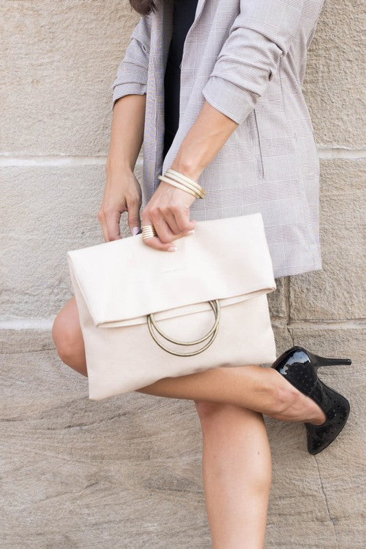 Woman carrying bone Safara Fold-Over Clutch with antique bronze O-ring accents.
