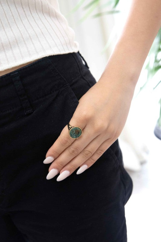 Woman wearing Ambition Stone Ring in Pine, styled with black pants and white top.