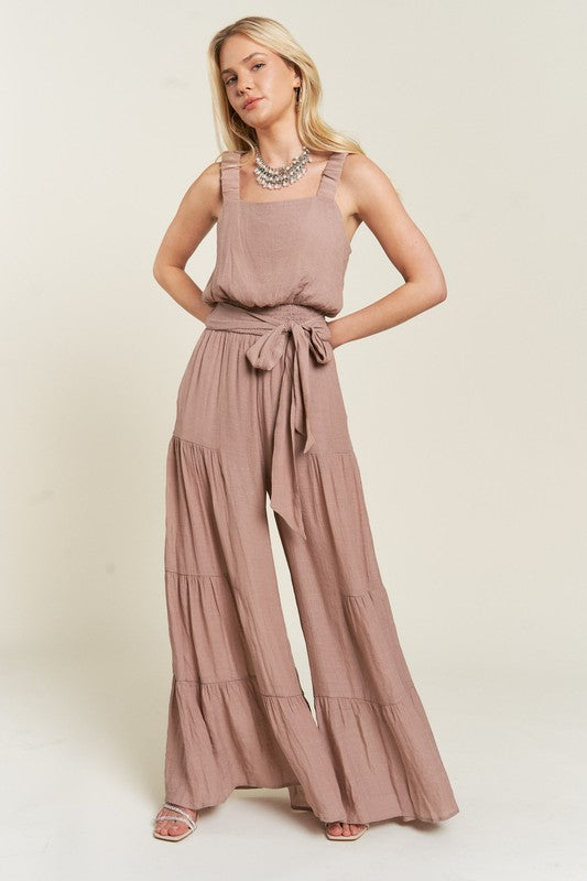 Full body view of model in taupe Chara Jumpsuit, highlighting flowy wide-leg tiers.