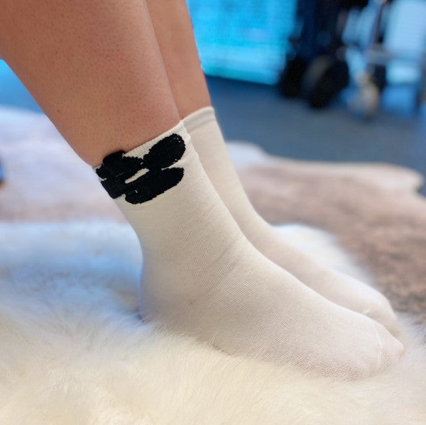 Woman wearing white flower Insiders Only Socks showing bold embroidered detail.