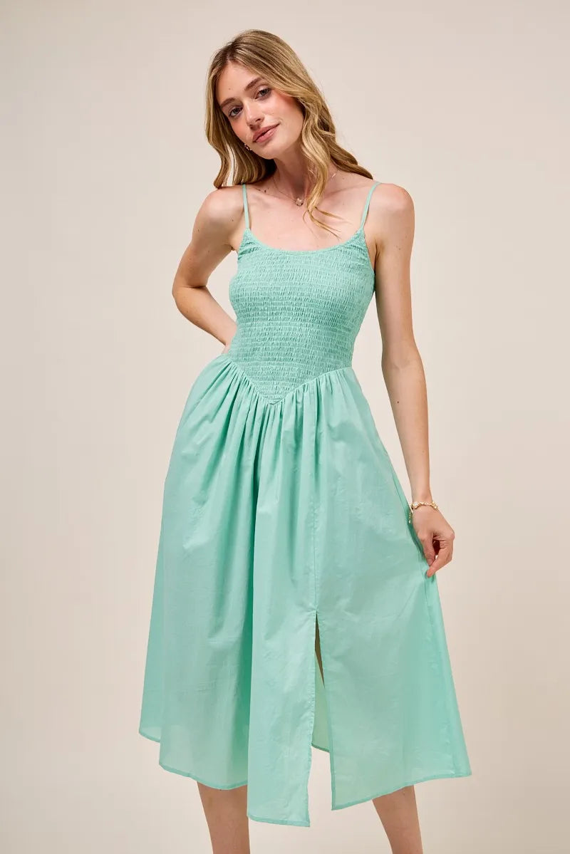 Cute front view pose of model wearing the Berkley Smocked Midi Dress in a fresh sage color, highlighting the flattering fit and breezy summer style.