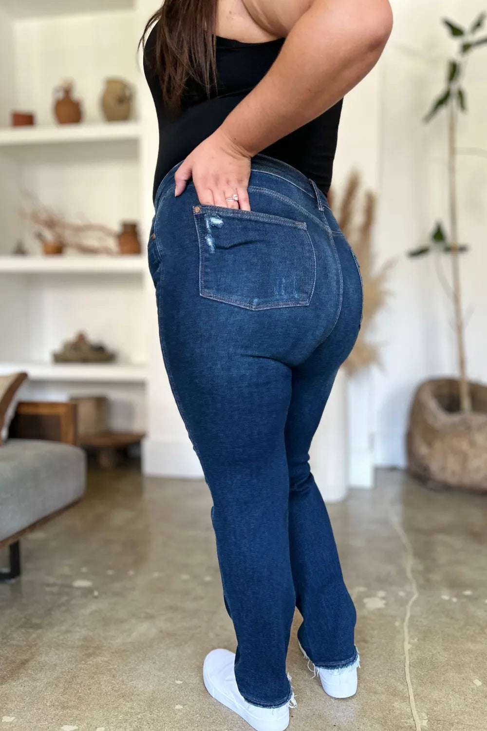 Back view of plus size model in Wynna Straight Jeans, showcasing heavy distressing and raw hem