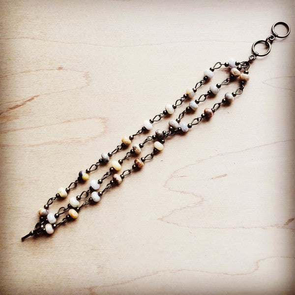 Flat laid view of handcrafted agate stone bracelet showing triple strand design.