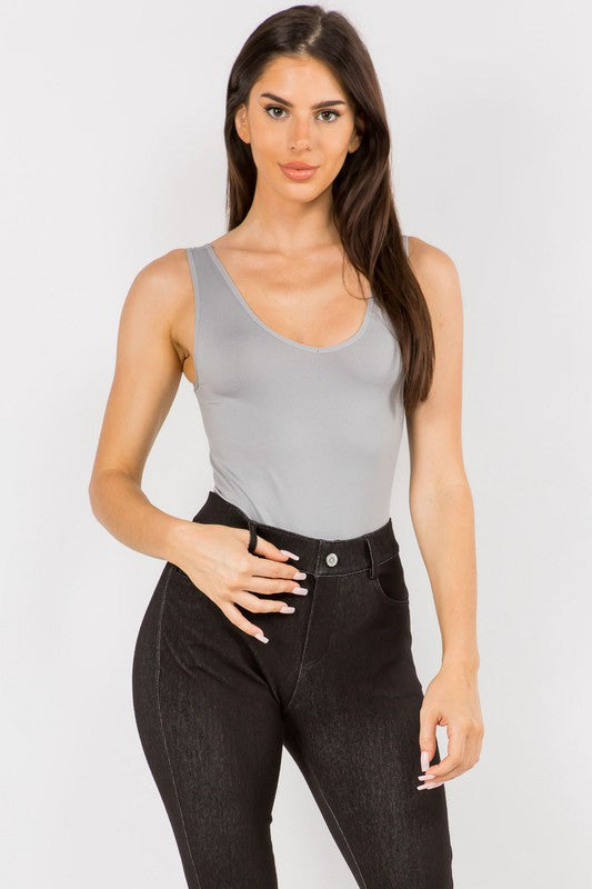 Woman wearing the Gray Tru V-Neck Tank Bodysuit with black pants, front view highlighting reversible neckline and seamless fit.