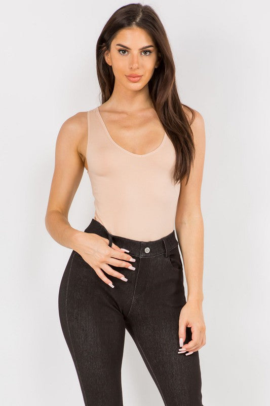Woman wearing the Light Mocha Tru V-Neck Tank Bodysuit with jeans, front view highlighting reversible neckline and fitted silhouette.