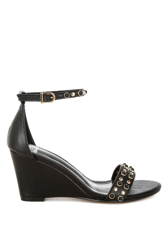 Side view of black leather wedge sandals with studded strap.