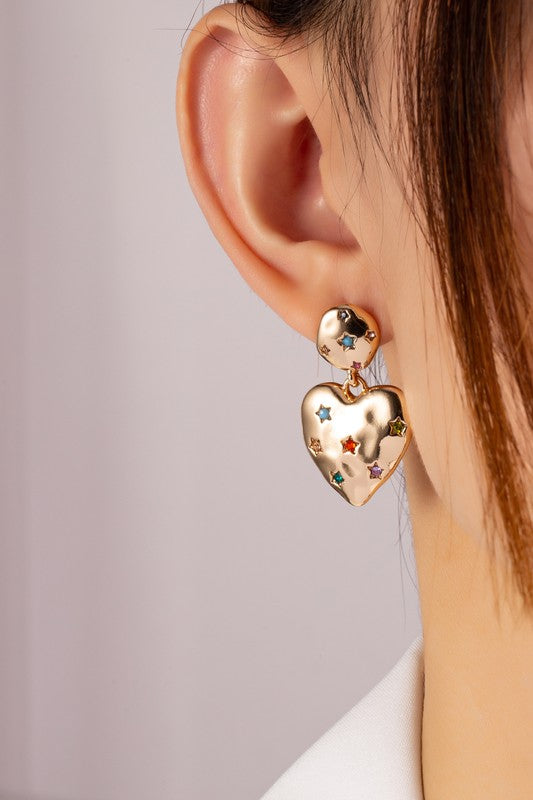 Woman wearing gold-plated Puffy Heart Earrings with rhinestone stars, adding sparkle and charm to her look.