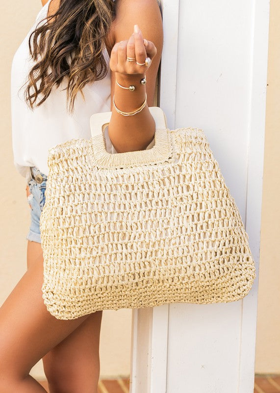 Straw Elinie Oversized Tote with woven straw design, natural wood handles, and zipper closure for secure summer storage.