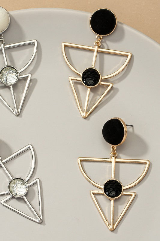 Earrings feature a velvet stud and geometric cutout design. Gold variant has and a textured black stone embedded in the cutout, while the silver variant has a white stone. They are 2.5 inches long.