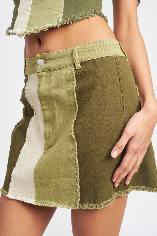 Close-up of Kassiani Olive Combo mini skirt showing color block pattern, frayed seams, and raw hem detail.