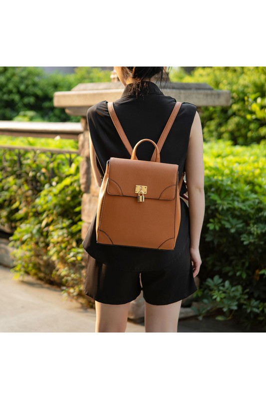 Woman carrying brown Sansa backpack with gold-tone hardware in casual outfit.