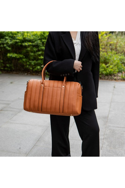 Luana Quilted Duffle Bag in Brown, held by handle in crook of elbow with gold-tone accents.