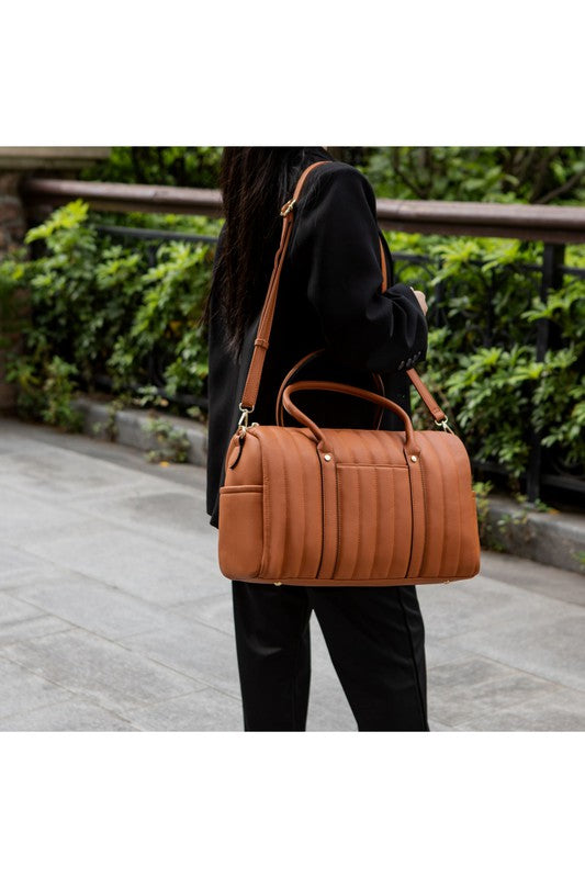 Luana Quilted Duffle Bag in Brown, worn over shoulder with adjustable strap and quilted design.