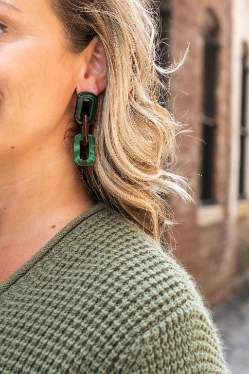 Woman wearing chunky amber and forest green resin chain-link earrings with hypoallergenic posts.