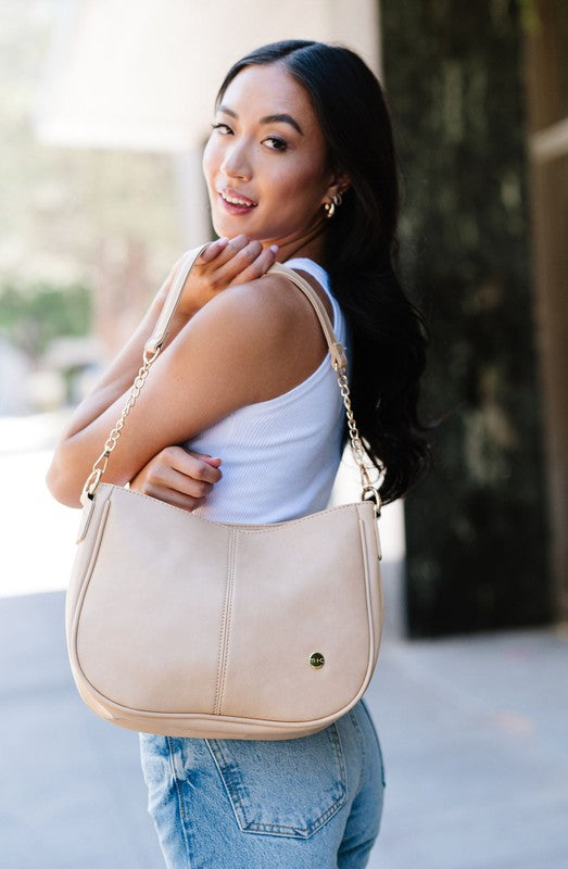 Biscuit vegan leather Marissa bag with gold accents, slim profile, and polished chain strap.