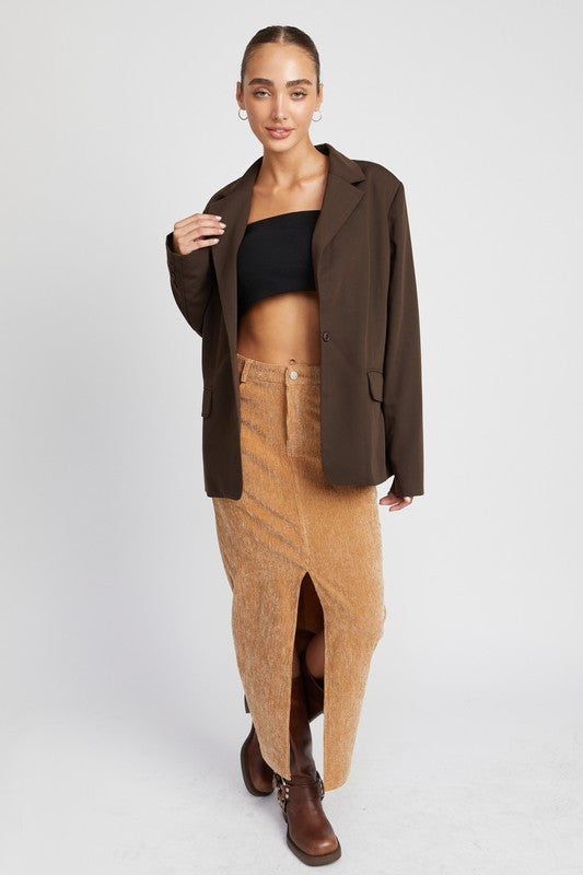 Model wearing Rasha Corduroy Mid Skirt With Front Slit, styled with blazer and boots.