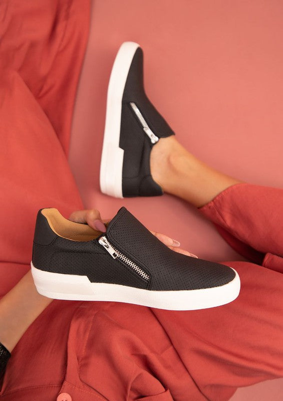 Black slip-on sneakers with a round toe design and side zippers.