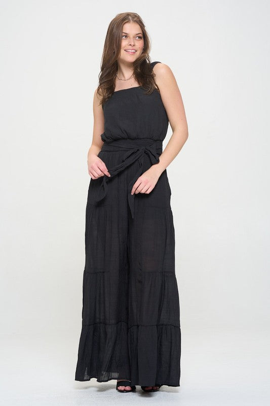 Front view highlighting tiered wide-leg silhouette and tie belt in black jumpsuit.