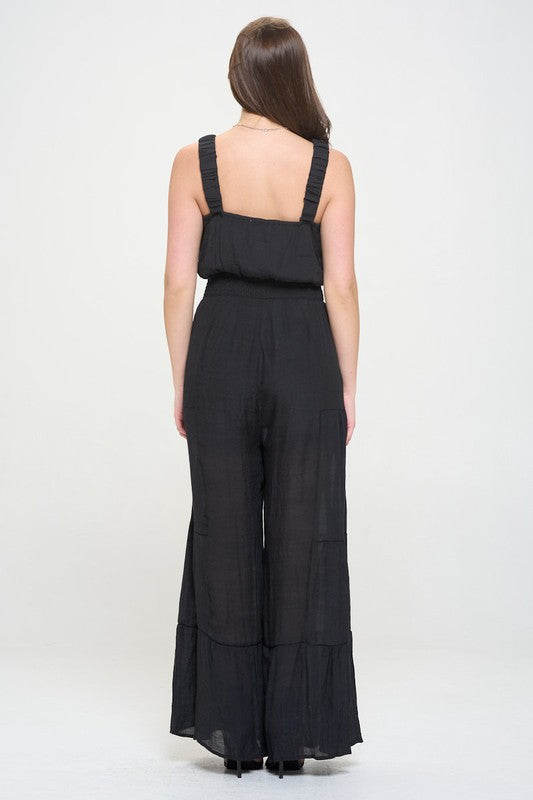 Back view of black Chara Jumpsuit, showcasing ruffled straps and tiered wide-leg style.
