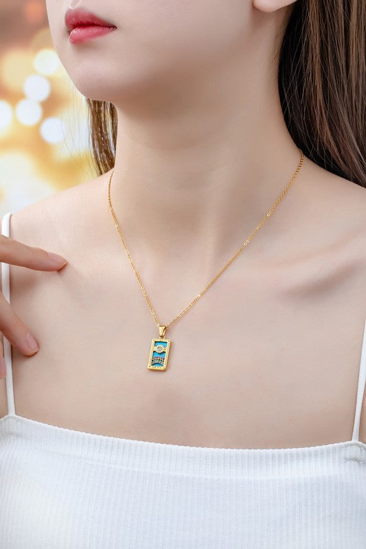 Woman wearing Tarot Card Sun Pendant Necklace with turquoise background, rhinestone rainbow, and gold-tone chain