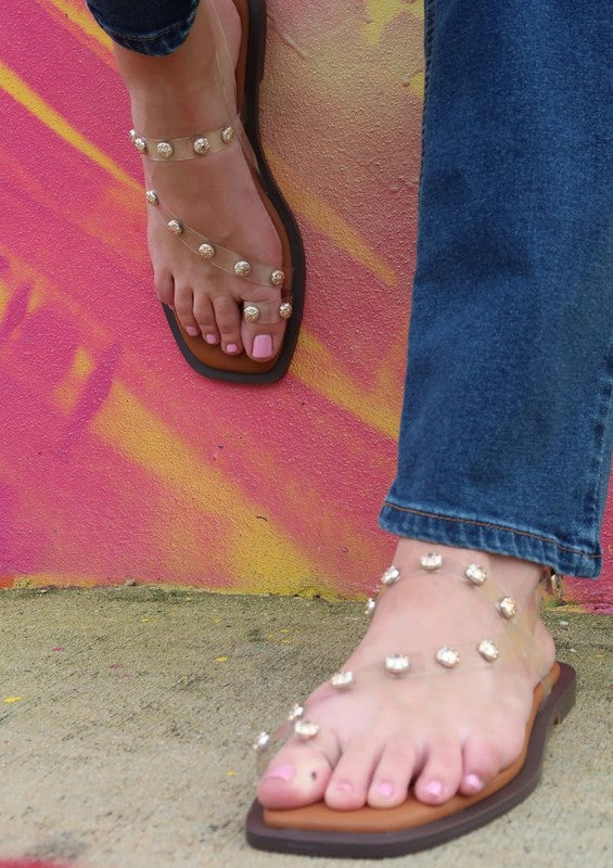 Close-up of clear Dara Stud Sandals showing transparent strap detail and studs.
