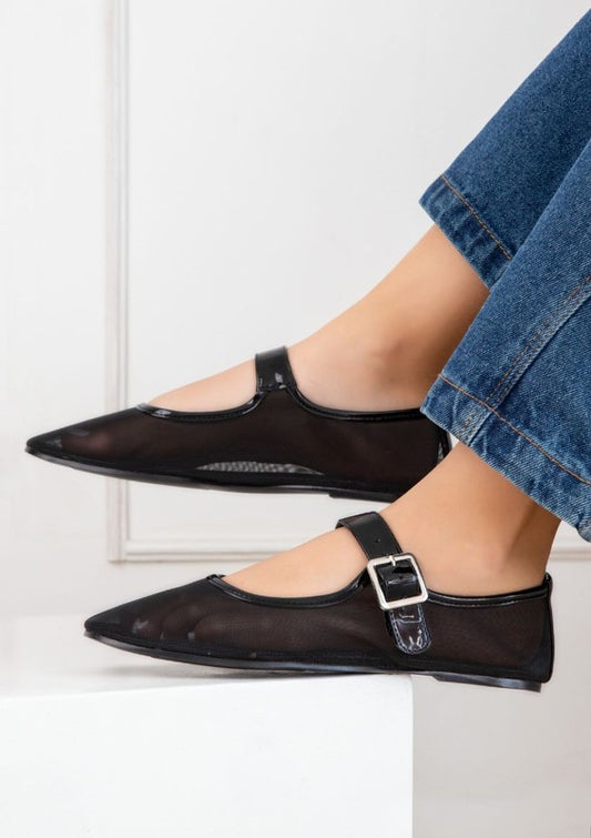 Woman wearing black mesh ballerina flats with adjustable strap and flat heel.