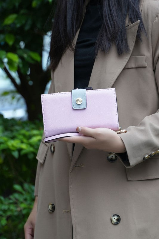 Woman holding MKF Collection Solene wristlet wallet in pink Saffiano vegan leather with gold-tone accents.