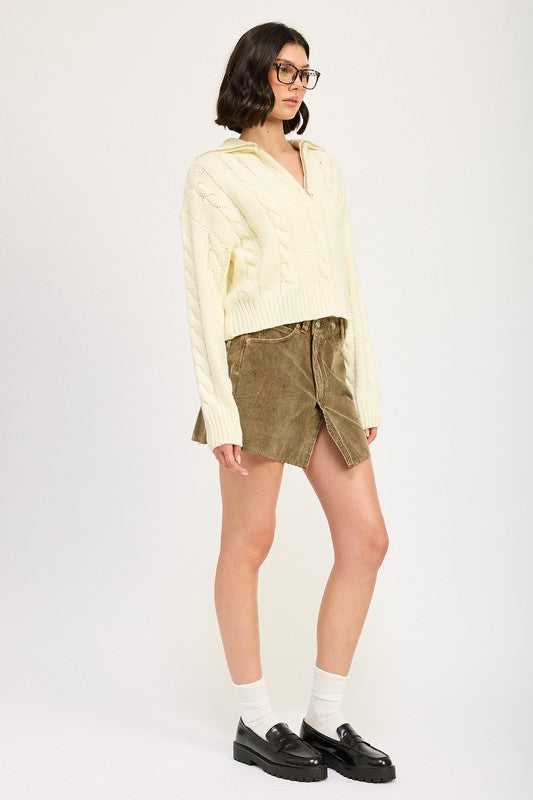 Side view of cream Daina cable knit cropped sweater highlighting relaxed fit and ribbed hem.