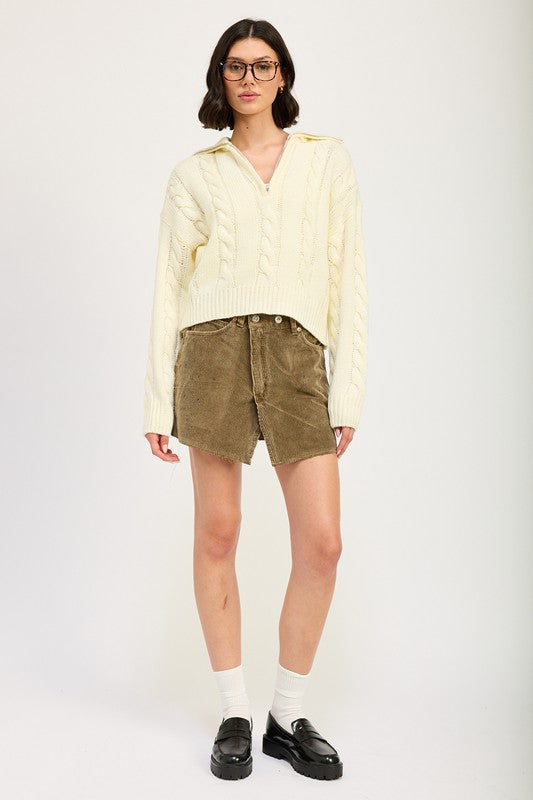Full body view of cream cropped Daina cable knit sweater paired with shorts for a chic look.