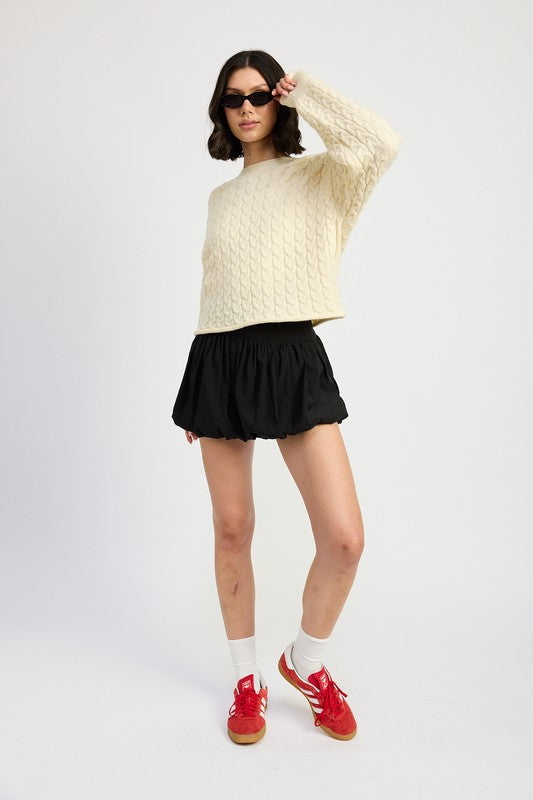 Full body view of Kuuma Sweater styled with black skirt and sunglasses for a trendy look.