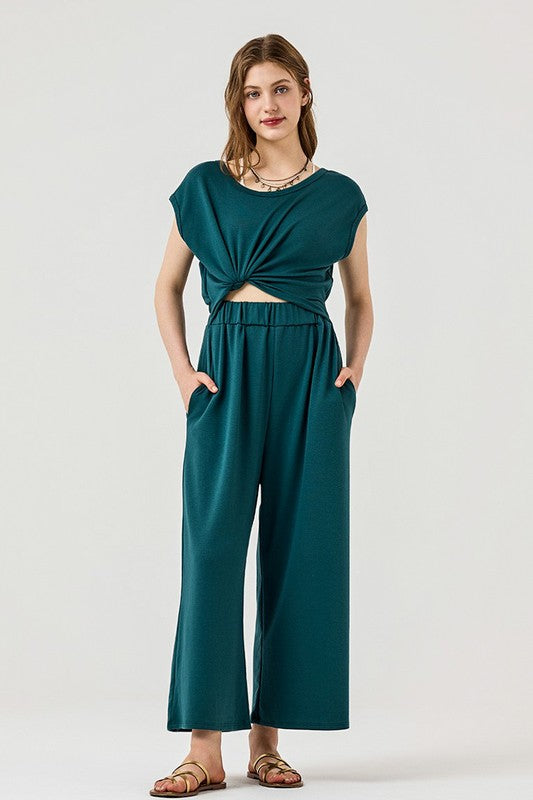 Full body view of model wearing Kora Wide Leg Jumpsuit in forest green with twist-front.
