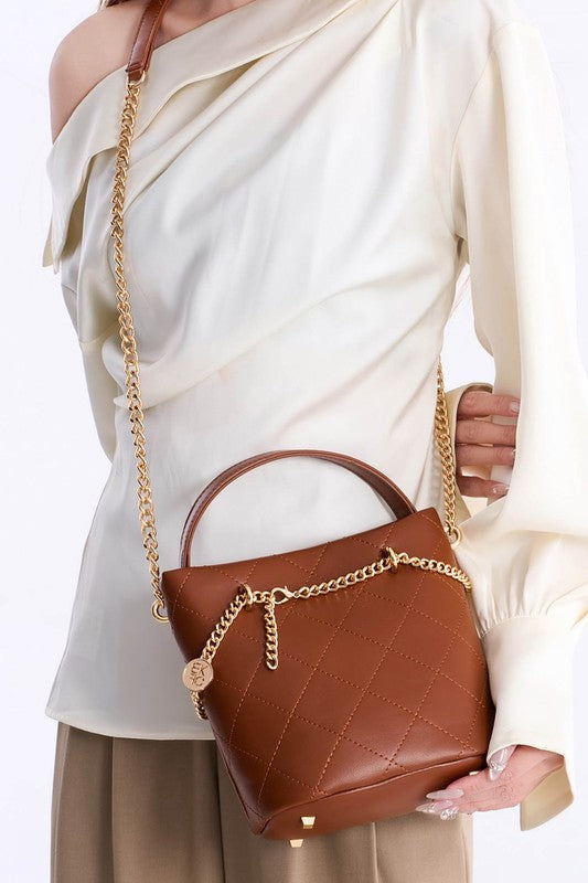 Brown MKF Damaris Crossbody Bag worn crossbody with quilted texture and gold chain strap.