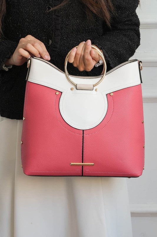 Woman holding peach Kylie satchel by top handle, showing two-tone design.