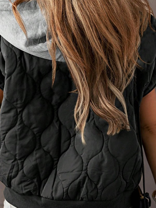 Back view of model wearing the Meara Oversized Drawstring Hooded Zip Up Puffer Vest in black, highlighting the textured pattern and contrasting gray hood.