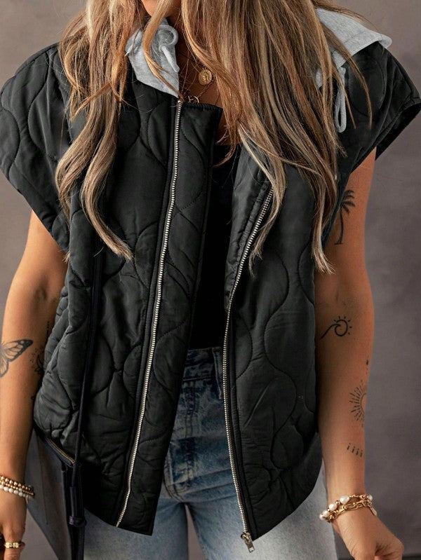 Front view of the Meara Oversized Puffer Vest in Black, featuring zip-up closure and gray hood, styled for a casual fall look.