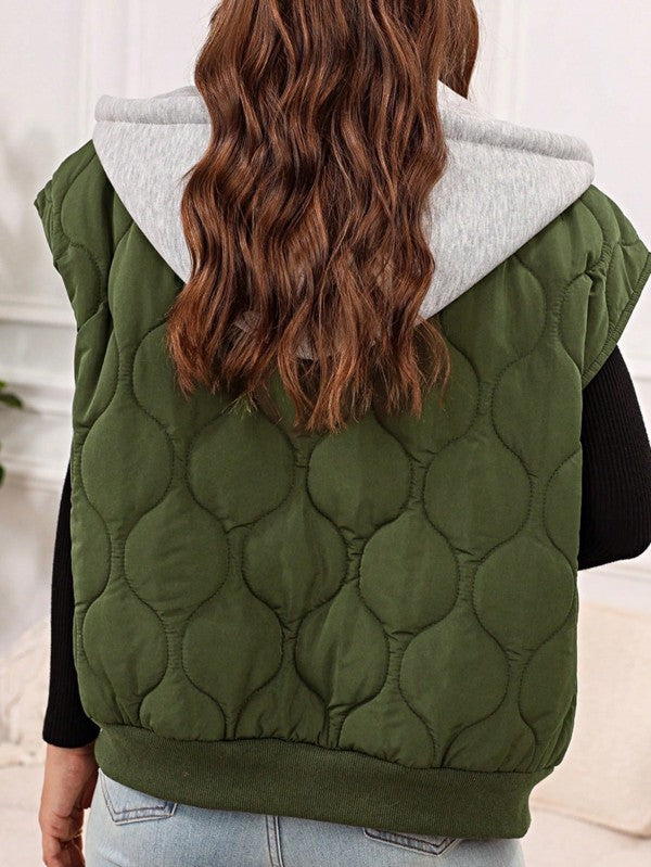 Back view of model wearing the Meara Oversized Puffer Vest in Olive, highlighting the unique puffer pattern and contrasting gray hood.