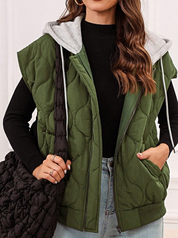 Front view of model wearing the Meara Oversized Drawstring Hooded Zip Up Puffer Vest in Olive, styled with jeans and an oversized bag for a laid-back fall look.