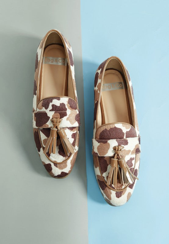 Top view of Moraug faux suede loafers showcasing cowprint pattern, tassel detail, and cushioned insole – stylish flat by Rag Company