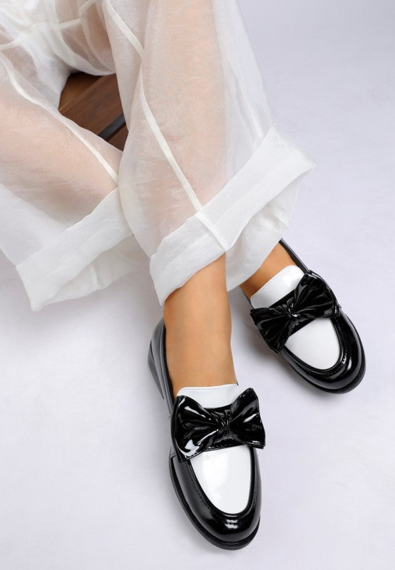 Model side view wearing Araminta Classic Chunky Bow Loafers in Black showing bow and rounded toe