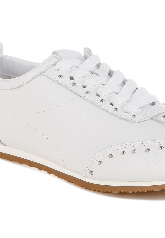 Close-up of white Odaya Studded Leather Sneakers by Rag Company, highlighting soft leather texture, stud embellishments, and contrast sole detail.