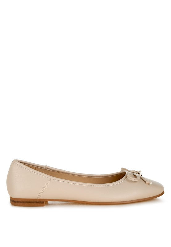 Side view of beige vegan leather flats featuring bow embellishment, cushioned insole, and flat heel for versatile wear.