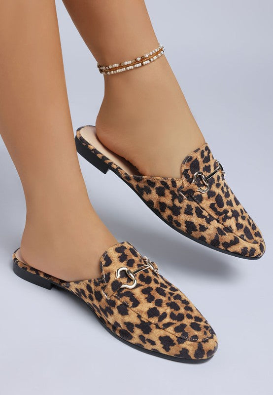 Woman modeling Alpine Horsebit Mules, showing inner and outer side views with chic leopard print and horsebit detail.