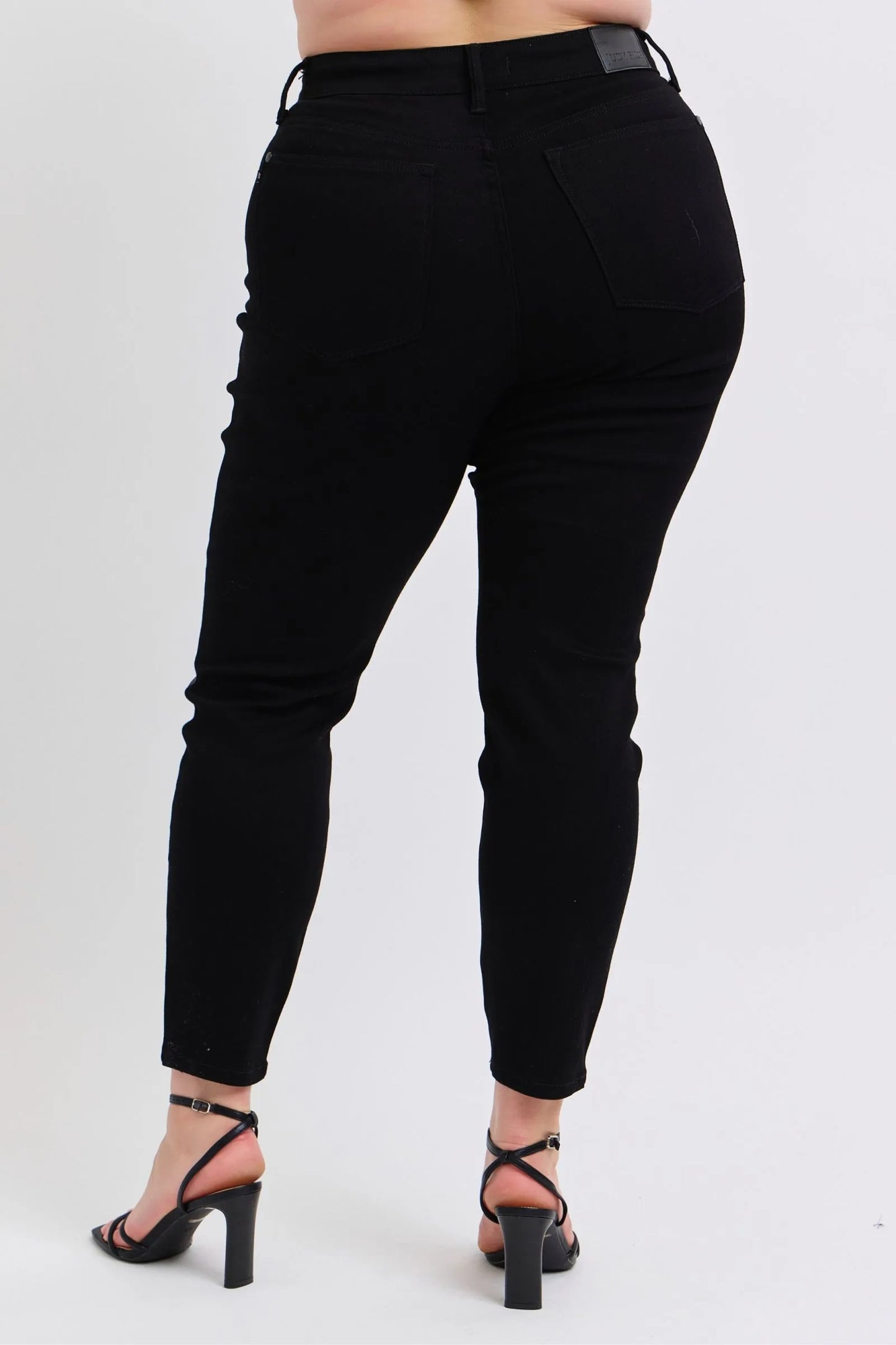 Plus model showing back view of Kat black faux leather skinny pants with high waist, skinny fit, and pocket detail.