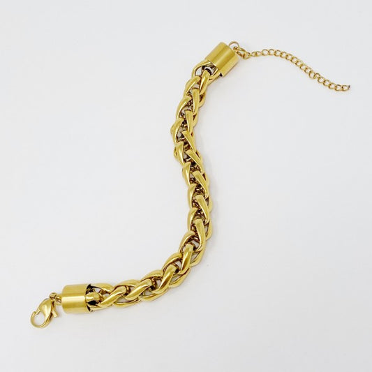Gold chain bracelet with bold interlocking links shown unfastened in curved flat lay