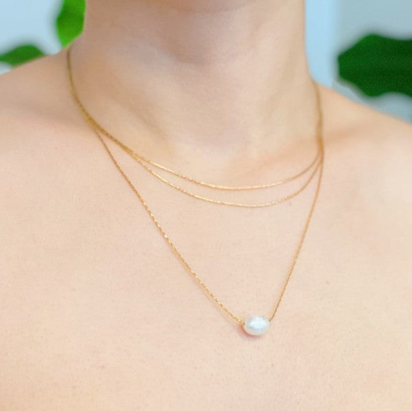 Woman wearing layered freshwater pearl pendant necklace close-up