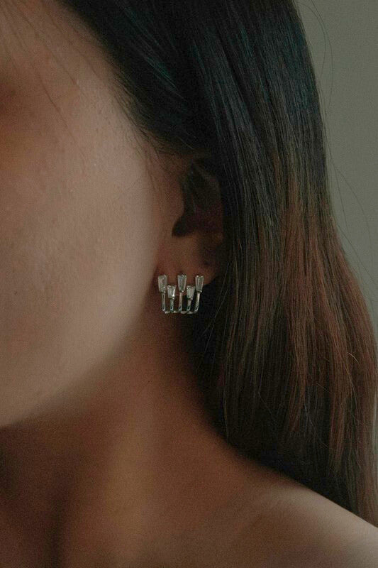 Woman wearing Kalimba Silver Baguette Post Earrings, showing petite sterling studs with five shimmering baguette stones.