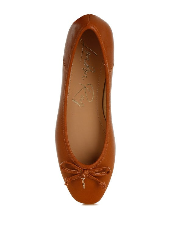 Top view of tan vegan leather ballerinas with bow accent, round closed toe, and sleek vegan leather finish.