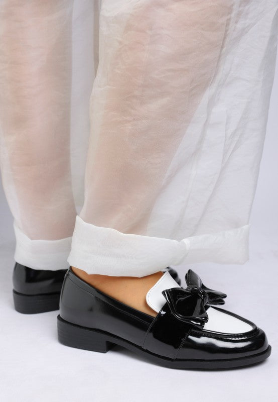 Model close up of Araminta Classic Chunky Bow Loafers in Black showing polished finish and detail