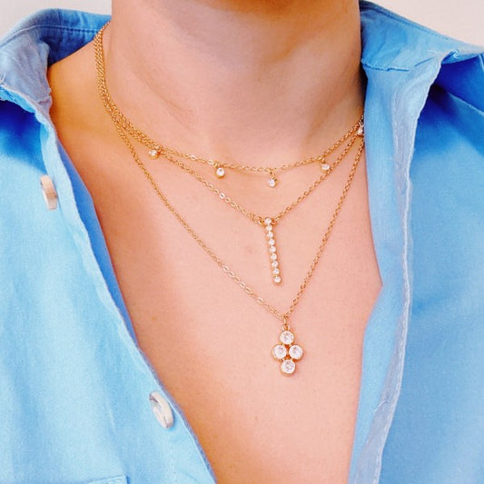 Woman wearing necklace: Gold layered chain necklace with bezel crystals styled with blue blouse.
