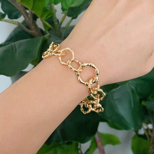 Model wearing Artfully Linked Chain Bracelet featuring bold, textured gold links